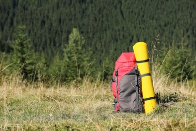 Photo of Backpack with sleeping mat on grassy hill, space for text. Mountain tourism