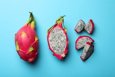 Delicious cut and whole white pitahaya fruits on light blue background, flat lay