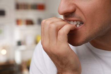 Photo of Man biting his nails indoors, closeup. Bad habit