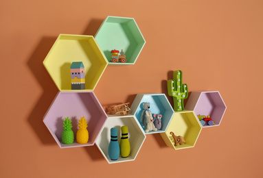Hexagon shaped shelves with toys on orange wall. Interior design