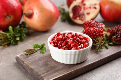 Delicious ripe pomegranate kernels in bowl on grey table