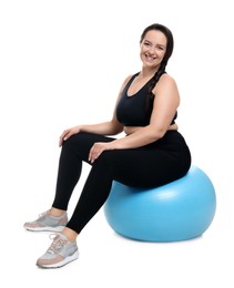 Happy overweight woman sitting on fitness ball against white background
