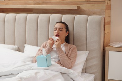 Sick young woman with napkins in bed at home