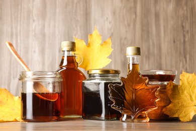 Bottles and jars of tasty maple syrup on wooden table