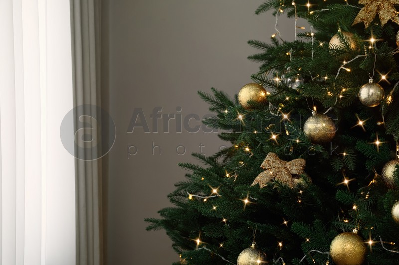 Christmas tree with beautiful decorations and string lights indoors, space for text