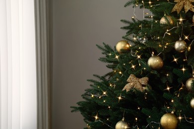 Christmas tree with beautiful decorations and string lights indoors, space for text
