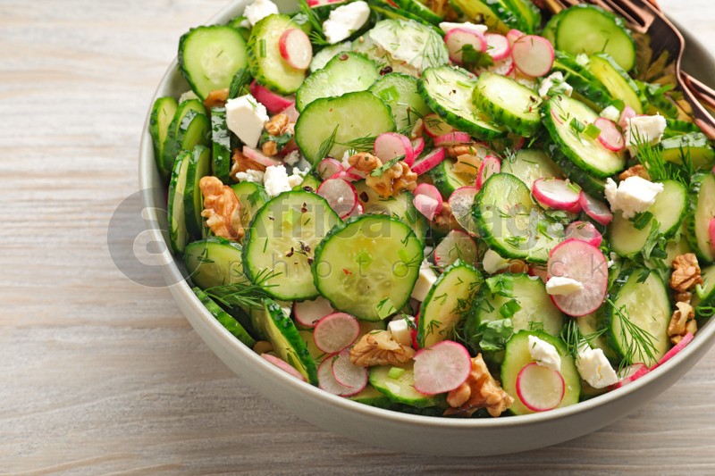 Bowl of delicious cucumber salad on white wooden table, closeup