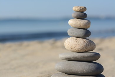 Photo of Stack of stones on sandy beach, closeup. Space for text
