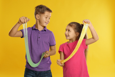 Happy children with slime on yellow background