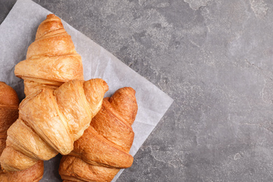 Tasty fresh croissants on grey table, flat lay. Space for text