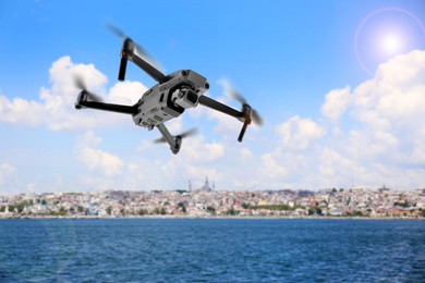 Modern drone flying over sea and blurred cityscape on background. Aerial survey