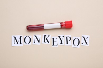 Word Monkeypox and test tube with blood sample on beige background, flat lay