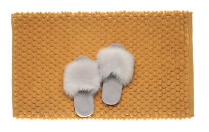 Soft orange bath mat and slippers isolated on white, top view