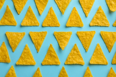 Photo of Flat lay composition of tasty tortilla chips (nachos) on light blue background