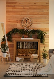 Photo of Cozy room interior with console table and conifer garland near wooden wall