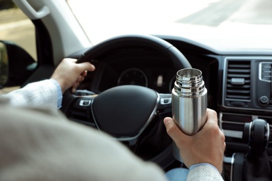Man with thermos driving car, closeup view