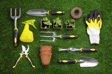 Photo of Flat lay composition with gardening tools and plants on green grass