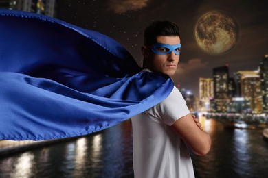Man wearing wearing superhero costume and beautiful cityscape in night on background