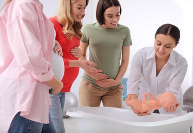 Pregnant women learning how to bathe baby at courses for expectant mothers indoors