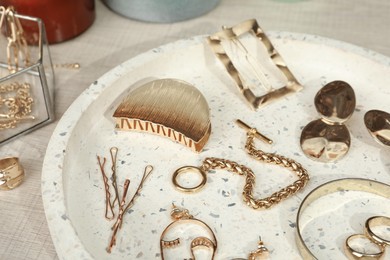 Stylish golden bijouterie and hair accessories on table, closeup
