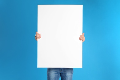 Man holding blank poster on blue background