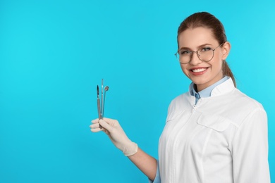 Female dentist holding professional tools on color background. Space for text