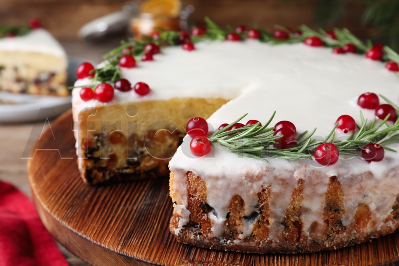 Photo of Traditional Christmas cake decorated with rosemary and cranberries on tray, closeup