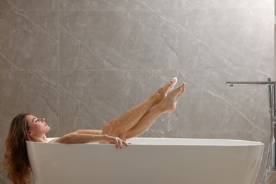 Beautiful woman taking bath with foam indoors