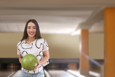 Young woman with ball in bowling club. Space for text