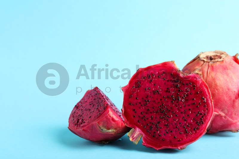 Delicious cut and whole red pitahaya fruits on light blue background. Space for text