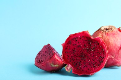 Delicious cut and whole red pitahaya fruits on light blue background. Space for text
