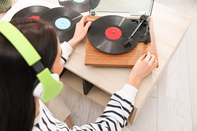 Woman listening to music with turntable at home, above view