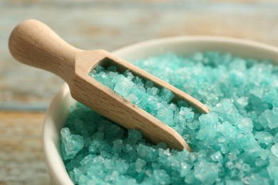 Photo of Bowl and scoop with turquoise sea salt on rustic table, closeup