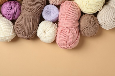 Soft woolen yarns on beige background, flat lay. Space for text