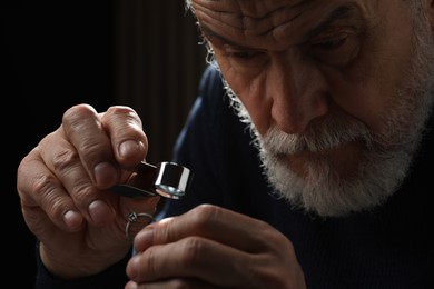 Photo of Professional jeweler working with ring on dark background, closeup