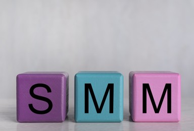 Colorful cubes with abbreviation SMM (Social media marketing) on grey background