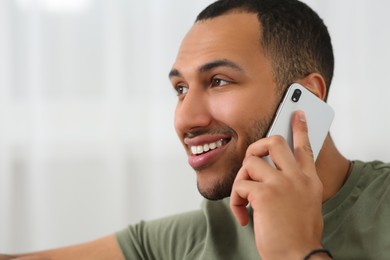 Photo of Smiling African American man talking on smartphone at home. Space for text