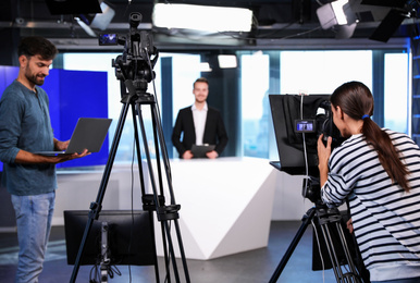 Photo of Presenter, director and video camera operator working in studio. News broadcasting