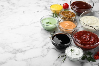 Many different sauces and herbs on white marble table. Space for text