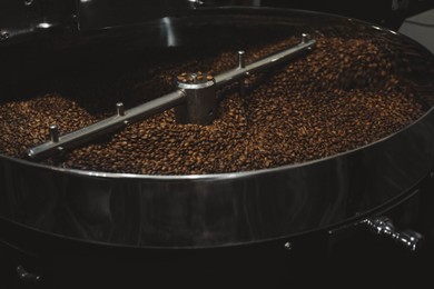 Photo of Modern coffee roaster machine with beans indoors, closeup