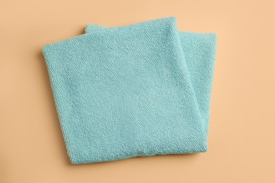 Clean soft folded towel on pale orange background, top view