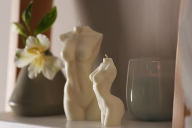 Beautiful body shaped candles and flower on shelf