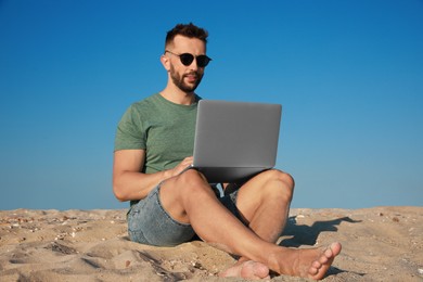 Man working with modern laptop on beach
