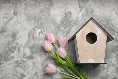 Beautiful bird house and pink tulips on light grey background, flat lay. Spring composition with space for text