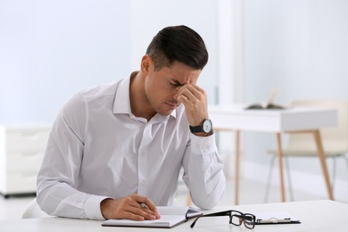 Stressed man at white table in office