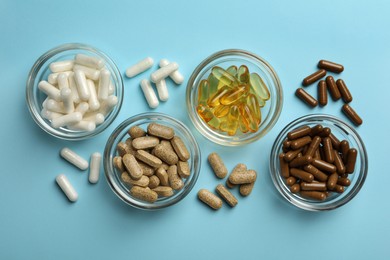 Different dietary supplements on light blue background, flat lay