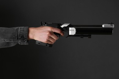 Gun shooting sport. Man aiming standard pistol on dark background, closeup