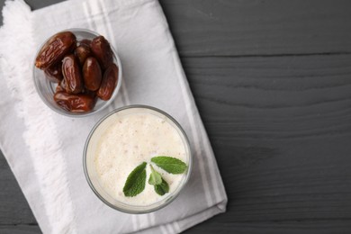 Photo of Glass of delicious date smoothie with mint and dried fruits on grey wooden table, flat lay. Space for text