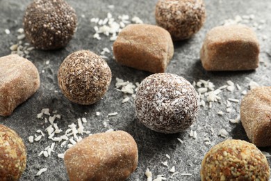 Different delicious vegan candy balls and desiccated coconut on grey table