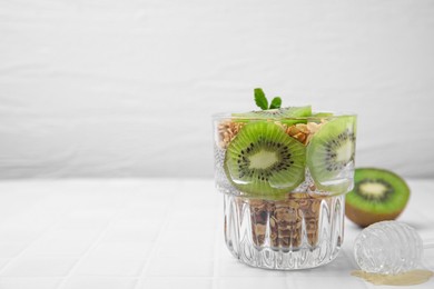 Photo of Delicious dessert with kiwi and muesli on white table. Space for text